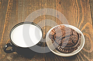 chocolate muffin and milk/chocolate muffin in a white plate and black mug with milk