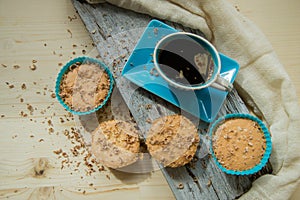 Chocolate muffin with soft cream and fresh blueberry powdered with sugar, cup of coffee, rustic background