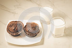 Chocolate muffins and glasses with milk/chocolate muffins and glasses with milk on a white marble background. Selective focus