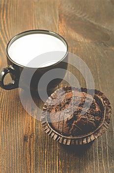Chocolate muffins and milk on a wooden background/chocolate muffin and a black mug with milk. Selective focus