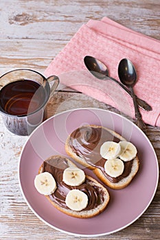 Chocolate-nut cream with banana on slices of bread with a Cup of tea.
