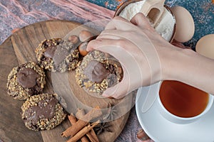 Chocolate nuts cookies on a wooden board served with cinnamons and a cup of tea