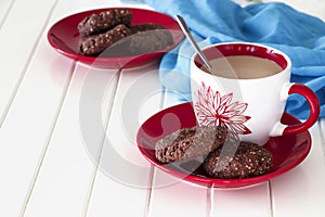 Chocolate oatmeal cookies and cup of milk tea. Blue and White wooden background.