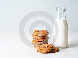 Chocolate oatmeal cookies and milk in bottle, healthy snack. Light background, grey light wall