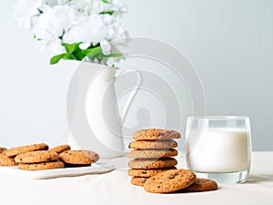 Chocolate oatmeal cookies and milk in glass, healthy snack. Light background, grey light wall