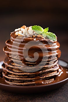 Chocolate pancakes with chocolate sauce and chopped nuts