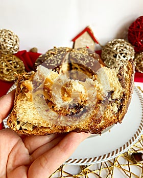 Chocolate panettone slice in hand with Christmas decorations . photo