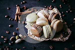 Chocolate pistachio coffee and vanilla flavored macaroons with pieces of chocolate cinnamon sticks coffee beans and pistachios