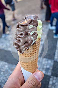 Chocolate and pistachio ice cream in a waffle cone in hand