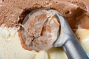 Chocolate plus vanilla ice cream with spoon and some digged out close up