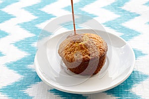 Chocolate is poured onto cake at plate on striped background.