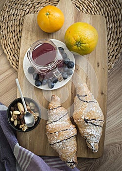 Chocolate powdered croissant with fruits, seeds, juice.