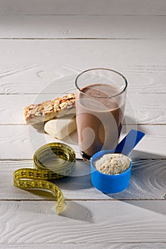 chocolate protein shake with energy bars and measuring tape on white