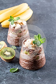 Chocolate pudding with chia seeds, kiwi and banana on gray table