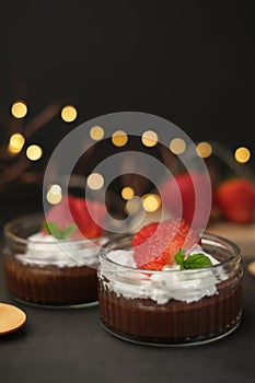 Chocolate pudding with cream and strawberry on bokeh. Sweet dessert and home cooking. vertical