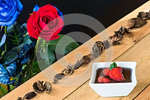 Chocolate pudding with strawberries and roses background