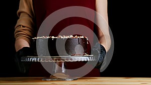 Chocolate raw cake with jam filling with hazelnuts on wooden table. vegan dessert closeup. woman confectioner hold chocolate cake