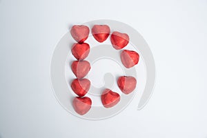 Chocolate red heart sweets in the form of the letter D for Valentine`s Day on a white background