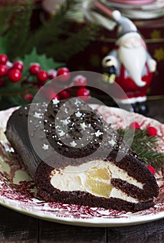 Chocolate roll stuffed with butter cream and pineapple on a Christmas background. Rustic style