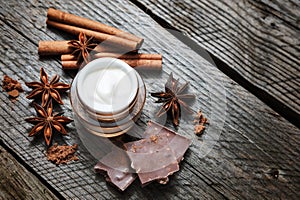 Chocolate skin treatment. Cosmetic jar with lotion, cocoa, anise, cinnamon sticks.