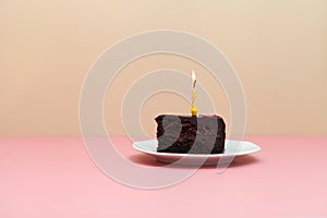 chocolate slice cake with candle on pink background-happy birthday tart -minimalistic image