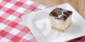 Chocolate souffle with thick chocolate ganache glaze served on a white plate on red plaid background