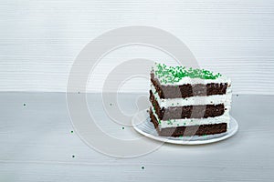 Chocolate sponge cake with buttercream interlayer located on the right. Green dusting