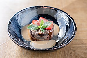 Chocolate sponge cake, with caramel, decorated with strawberries and mint leaf. Breakfast in the cafe, morning coffee