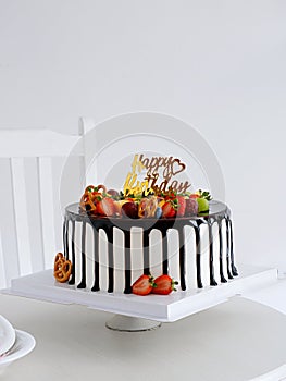 Chocolate and strawberry cake with a happy birthday sign on a white table with a white background