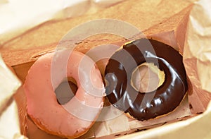 Chocolate and strawberry donuts packing in brown paper bag