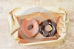 chocolate and strawberry donuts packing in brown paper bag