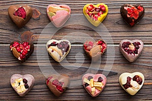 chocolate sweets in the form of a heart with fruits and nuts on a colored background. top view with space for text