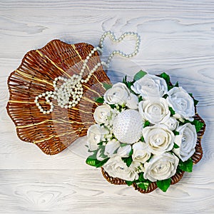 Chocolate sweets in a package in the form of white paper roses, pearl beads lie in a seashell of rattan