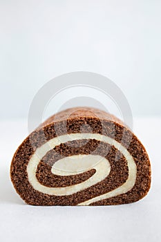 Chocolate swiss roll closeup isolated on white background. Delicious homemade biscuit with dark chocolate and cream filling.