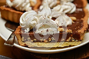 Chocolate tart cake with nuts and whipped cream on top.