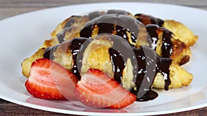 Chocolate testy croissants poured with chocolate served on plate with strawberries