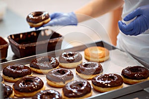 Chocolate topping on donuts in a candy workshop. Pastry, dessert, sweet, making