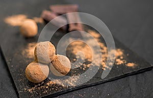 Chocolate truffle candy coated in cocoa powder against black background.