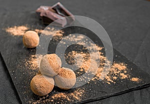 Chocolate truffle candy coated in cocoa powder against black background.