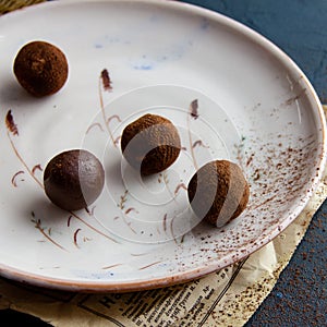 Chocolate truffle. Dark chocolate candy sprinkled with cocoa on ceramic plate on a dark background in rustic style