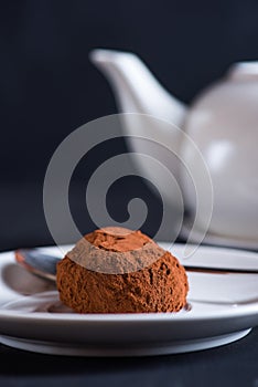 Chocolate truffle on white platter over dark background