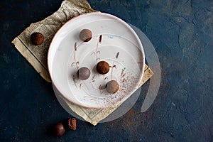 chocolate truffles on ceramic plate on dark blue background, top view