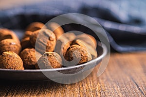 Chocolate truffles covered with cocoa powder on plate on wooden table