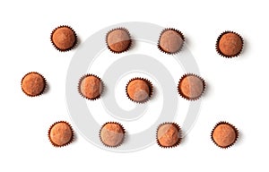 Chocolate truffles in individual paper baskets on a white background, top view