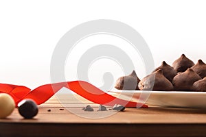 Chocolate truffles on white plate on wooden table with ribbon