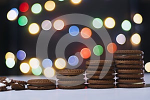 Chocolate-vanilla cookies stand like a ladder against the background of colorful bokeh.