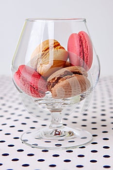 Chocolate, vanilla and strawberry macaroons in a glass vase