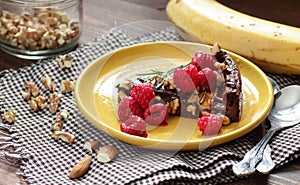 Chocolate vegan brownie cake with banana decorated with raspberry, walnut and rosemary