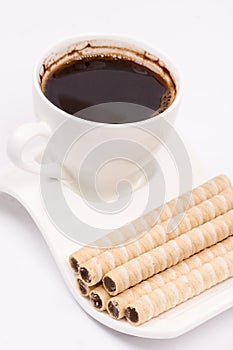 Chocolate wafer cream rolls and white cup of black coffee