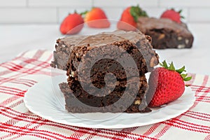 Chocolate and walnut fudge brownies with strawberries.  Close up